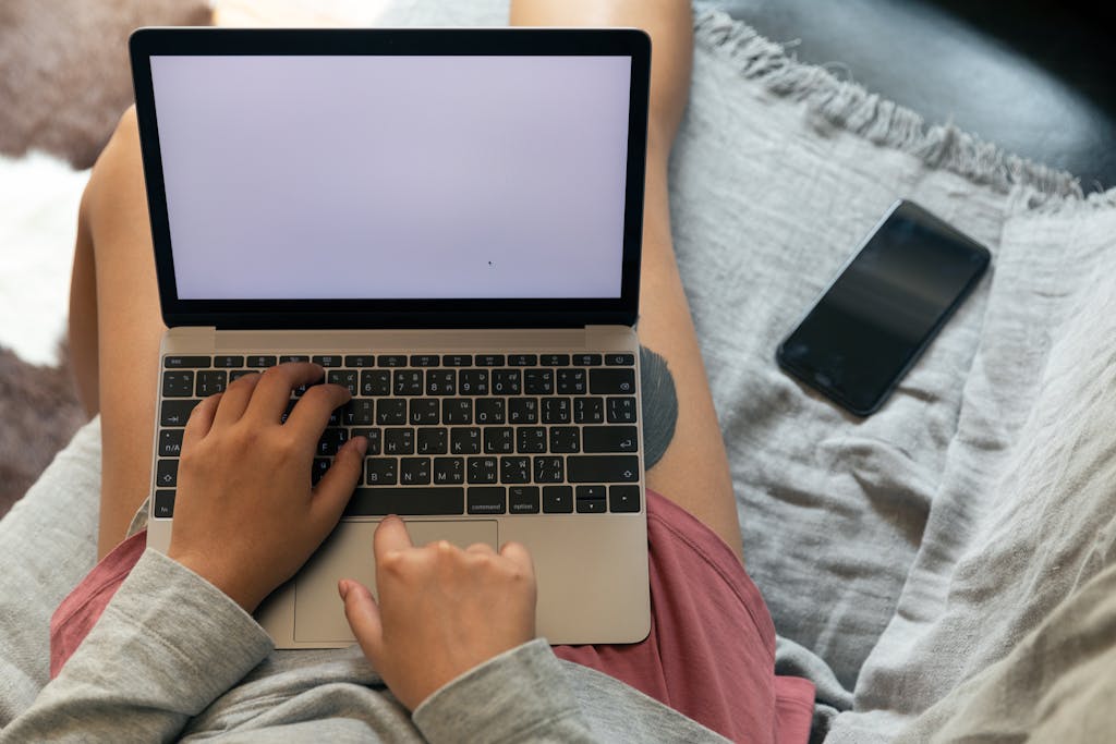 Crop unrecognizable freelancer typing on laptop with blank screen