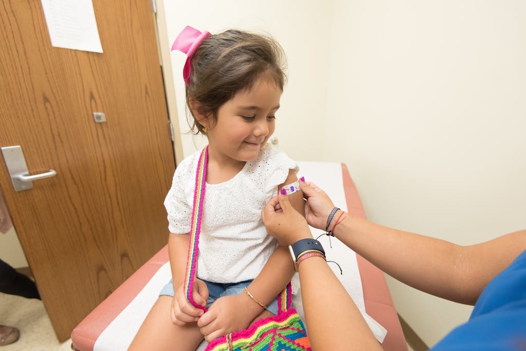 A cheerful young girl receives a band-aid after a vaccination at a clinic.